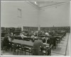 [Black and white photograph of students and study area at Earlsfort Terrace Library, University College, Dublin. Photograph shows open shelving to left middle-ground and bookcases with glass doors to centre and right middle-ground.]